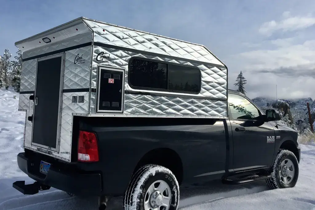 A lightweight truck camper capri cowboy standing on a snow-covered road