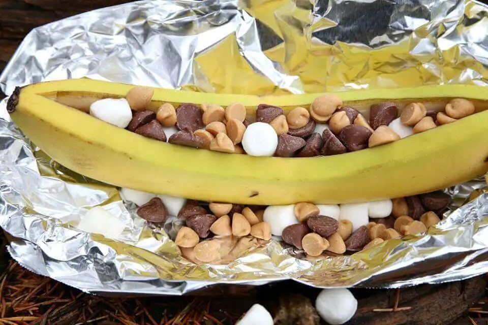 banana boats- camping dessert. unpeeled banana filled with marshmallows and chocolate chips on a foil. 