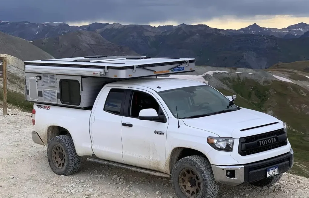 Four wheel hawk truck camper on a white truck standing on a mountain side road